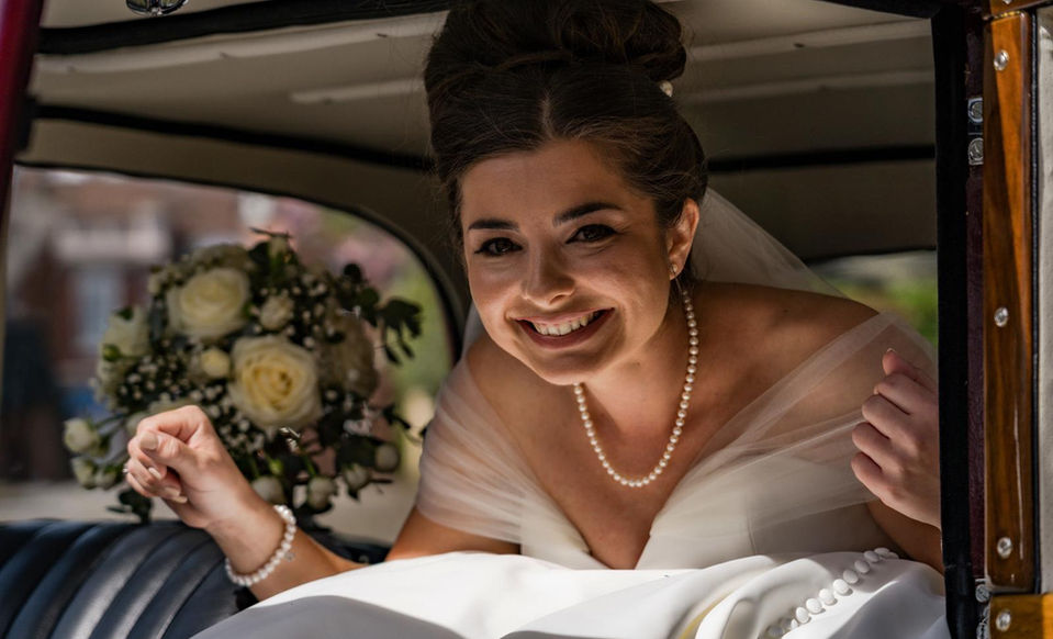 Joyful bride smiling to friends and family in car