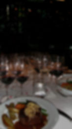 A detailed view of a gourmet dinner plate paired with selected wines at a YMC curated dining event.