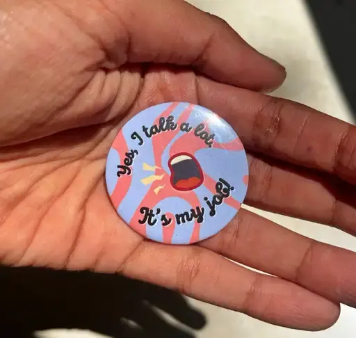 Hand holding button: "Yeah, I talk a lot. It's my job."