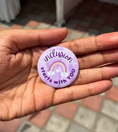 Hand holding purple button: "Inclusion starts with you"