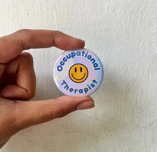 Hand holding Occupational Therapist button, smiley face