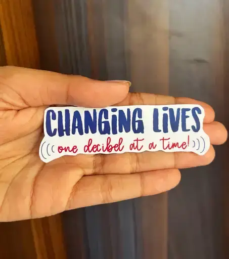 Hand holding 'Changing Lives, one daibd at a time' sticker
