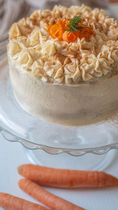Vista dall'alto di una Carrot Cake decorata con ciuffi di frosting al mascarpone, nastri di carota a spirale e un rametto di aneto fresco