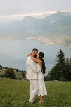 Couple kissing in front of Lake Lucerne and the mountains in the meadowof the hotel Villa Honegg on their marriage proposal photoshoot, in Switzerland