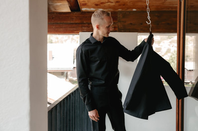 groom getting ready in the balcony holding his suit jacket