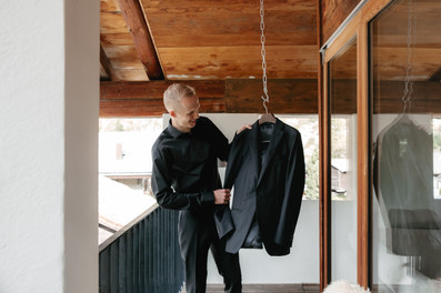 groom getting ready in the balcony holding his suit jacket