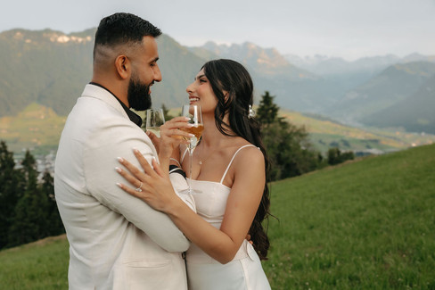 Couple hugging and sipping champagne in front of the hotel Villa Honegg on their marriage proposal photoshoot, in Switzerland