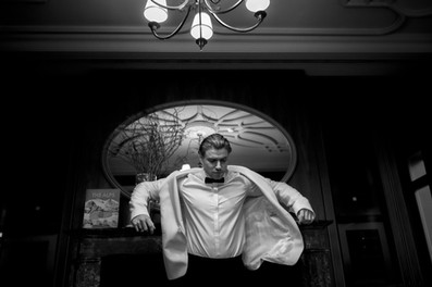 groom getting ready at cigar room in Villa Honegg Switzerland putting on jacket