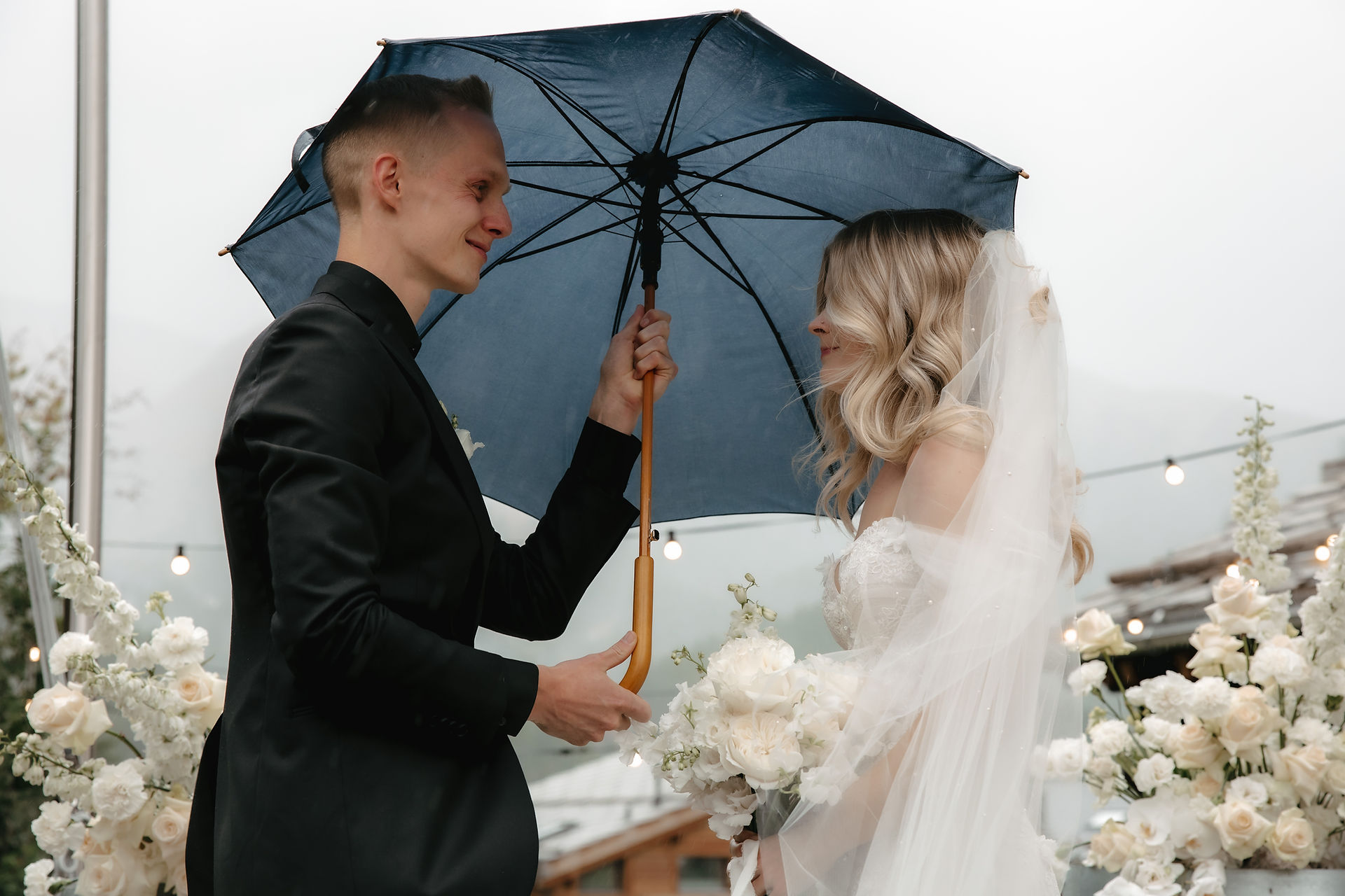 bride and groom under a blue umbrella during the ceremony wedding day at sonmmatten hotel in Zermatt