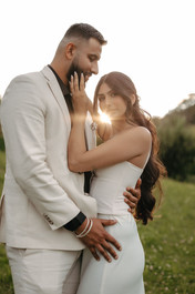 Couple hugging with the sun behind them, in a meadow in front of the hotel Villa Honegg on their marriage proposal photoshoot, in Switzerland