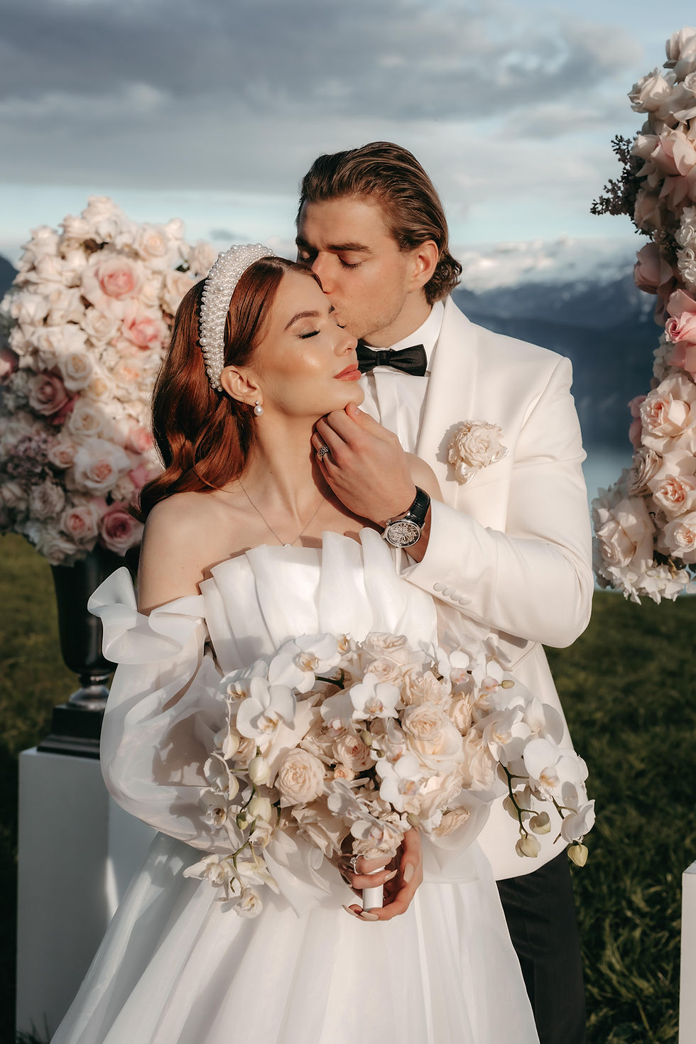 Bride and groom kissing in front of floral decorations at Villa Hönegg's terrace, after their destination wedding in Switzerland