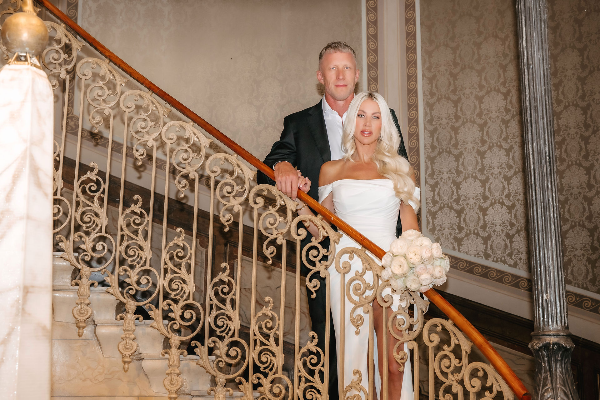 couple posing at staircase at hotel victoria jungfrau in Interlaken. An American elopement at Hotel Victoria-Jungfrau, Interlaken — vows in Lauterbrunnen, portraits at Blausee. A fine art Swiss wedding story
