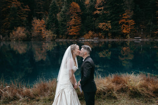 Bride and groom kissing in front of the Blausee in Switzerland