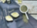 our large beeswax melts are leaf shaped and we add dried botanicals, in this instance rosemary is pictured next to our melts and the products are laid on an apron showing our Mill House name