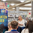 Autorin sitzt in der Romanabteilung der Stadtbibliothek Gütersloh