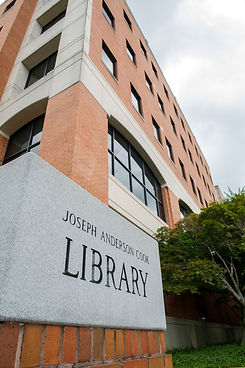Cook Library. Five floor red brick building with bushes inf front.