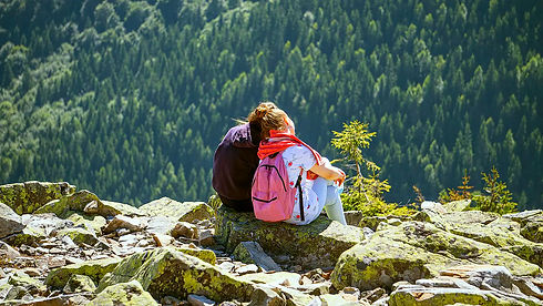 Paar sitzt auf Felsen, genießt die Aussicht auf grünen Wald.