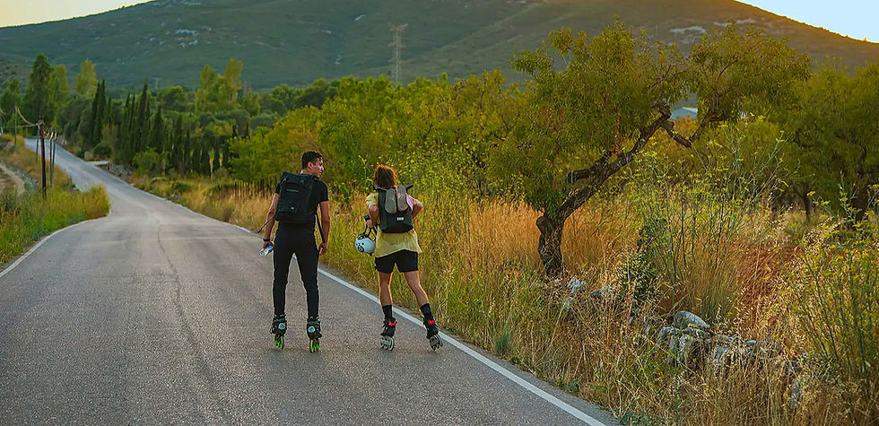 Zwei Personen inlineskaten auf kurviger Landstraße, grüne Hügel, Outdoor Training.
