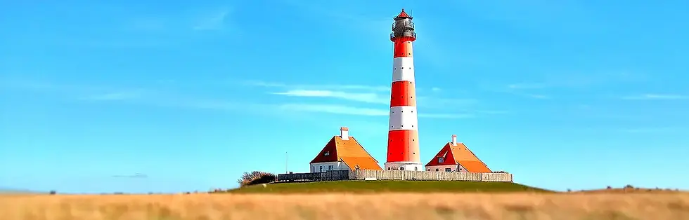 Roter weißer Leuchtturm im Schleswig-Holsteinischen Wattenmeer unter blauem Himmel.