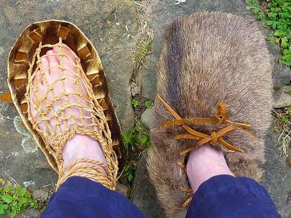 Zwei Füße in Stroh- und Pelzschuhen auf Steinen, Die Geschichte der Schuhe, Schuhe.