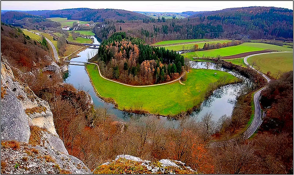 Landschaftsbild mit Fluss und grüner Wiese, Naturpark Obere Donau im Hintergrund.
