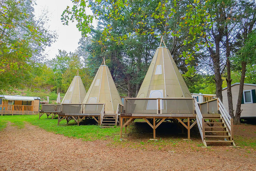 Drei helle Tipi-Zelte auf Holzplattformen im Wald. CAMPING.