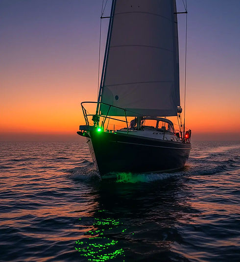 Segelboot auf dem Meer bei Sonnenuntergang mit grünem Navigationslicht.
