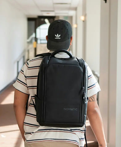 Person trägt schwarzen Rucksack in einem Flur.