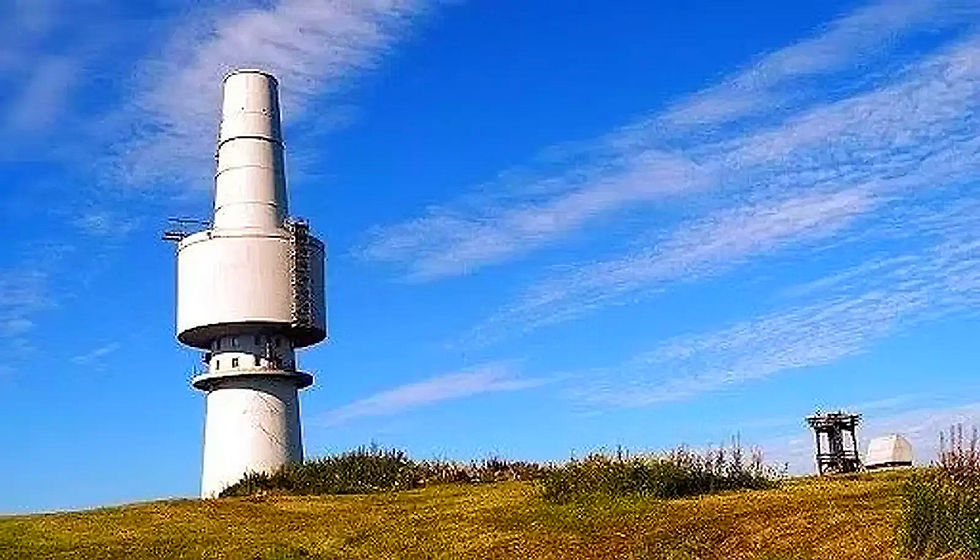 Ein hoher, weißer Turm vor blauem Himmel am Naturpark Fichtelgebirge.