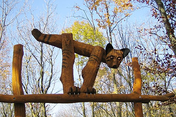 Holzskulptur einer Katze, die auf einem Balken balanciert und im Hainich steht.
