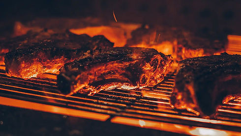 Mehrere dicke Steaks garen auf einem Grill über glühender Hitze.