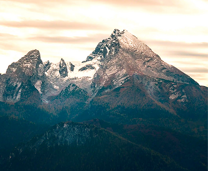 Majestätischer schneebedeckter Berggipfel vor dramatischem Himmel, alpine Landschaft.