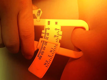 Hände verwenden Körperfettzange, zeigt "PRESS" und Skala 10-60 %.