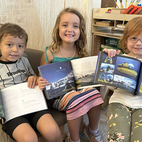 Three children, each holding up a book about a submarine