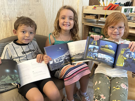 Three children, each holding up a book about a submarine