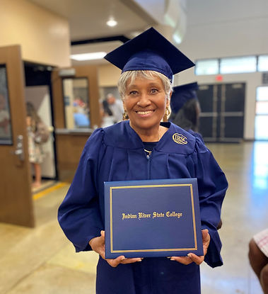 A woman in a cap and gown holds a diploma.