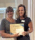 Two women stand. They are jointly holding a certificate