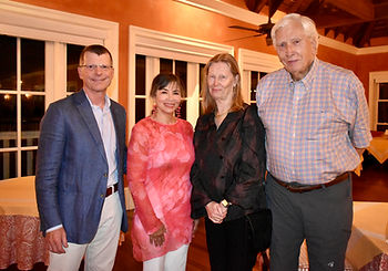 Four people smiling indoors, standing side by side. Warm-toned walls and soft lighting create a welcoming atmosphere.