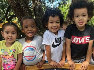 Four children stand in a group outside