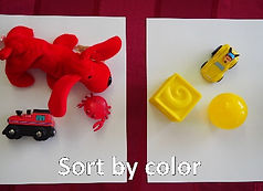 Two small groups of children's toys sorted by color. One group is red, the other is yellow.