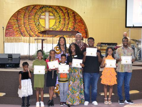 Group of people holding certificates, church backdrop