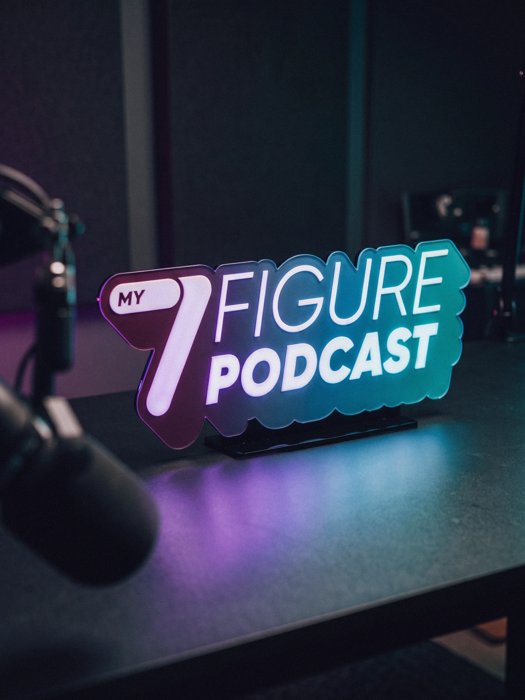 My 7 Figure Podcast logo displayed in a podcast recording studio