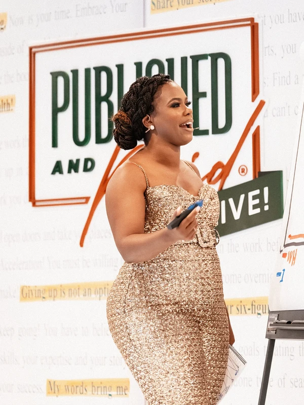 An event attendee in front of the Published And Paid Live branded backdrop.