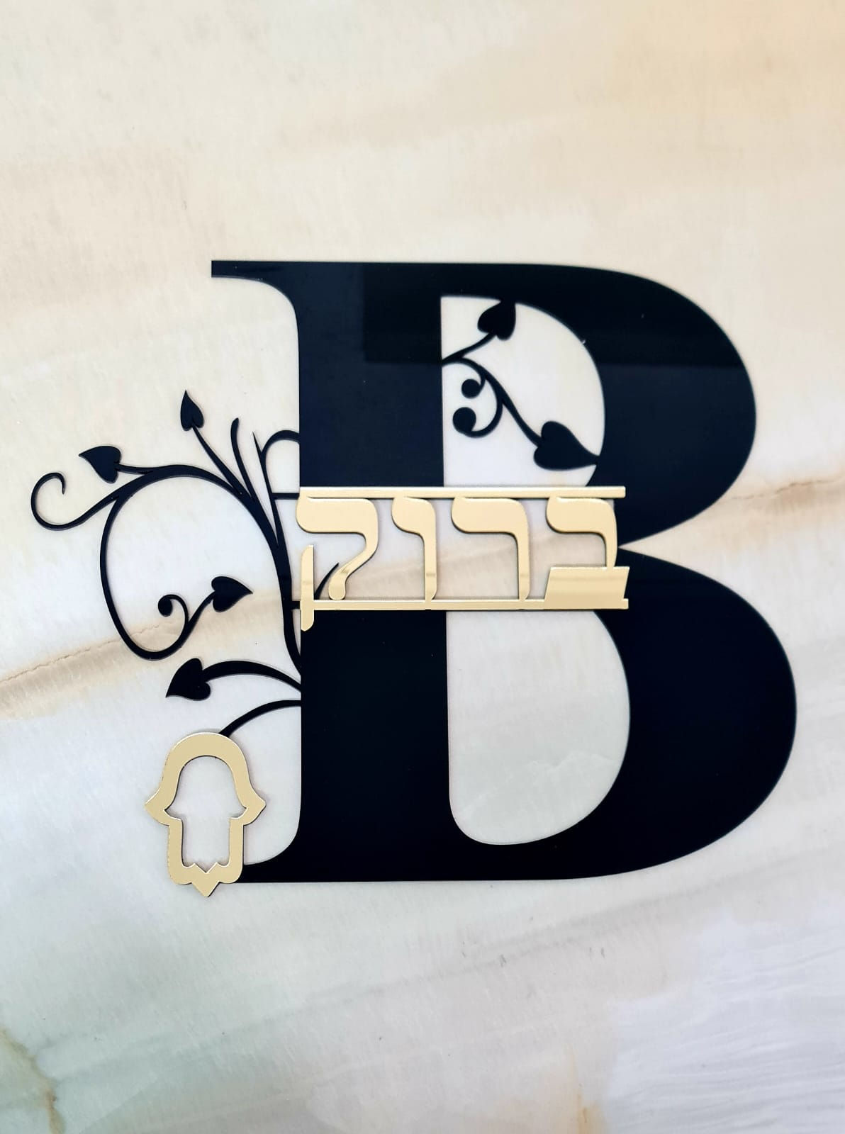 Decorative black letter B with Hebrew text and Hamsa