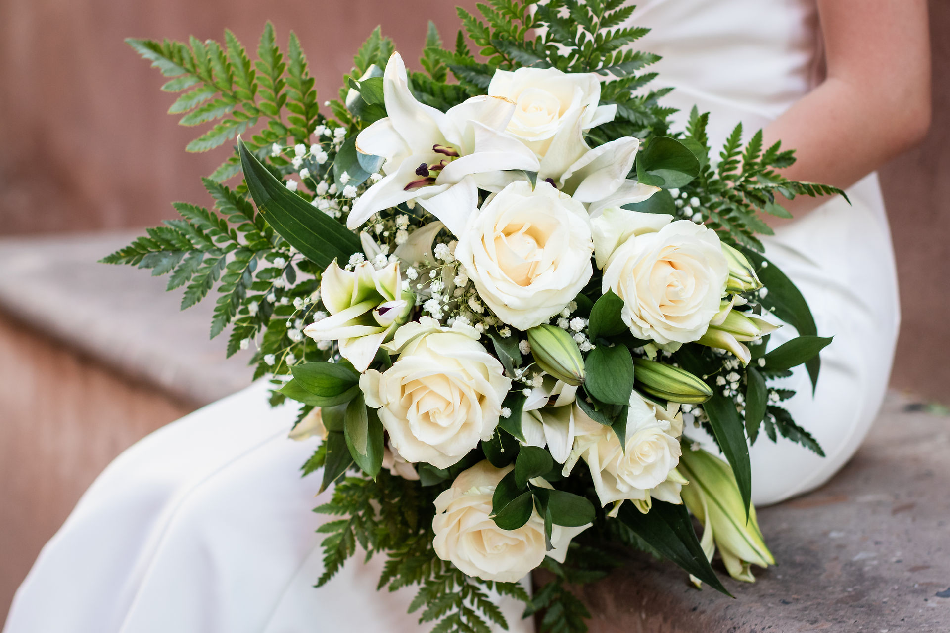 Close-up of white rose bridal bouquet with lilies and greenery at Mercado rooftop ceremony