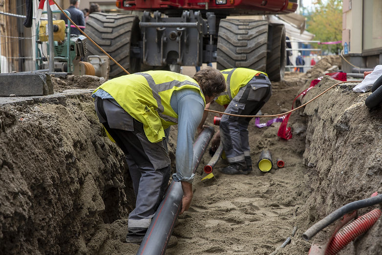 Two workers working on underground piping