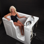 A woman in a black bathing suit sitting inside a walk-in tub with the door open