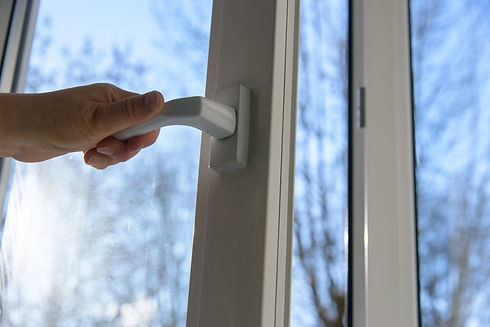 Une main ouvrant une poignée de porte vitrée