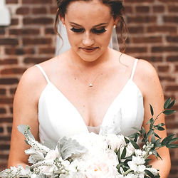 Woman in white dress with updo, holding bouquet, for event hair styling