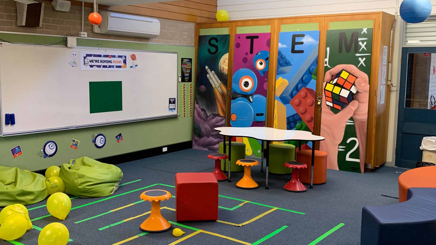 Bright STEM-themed mural with rockets, robots, Lego pieces, equations, and a Rubik’s cube for Cringila Public School.